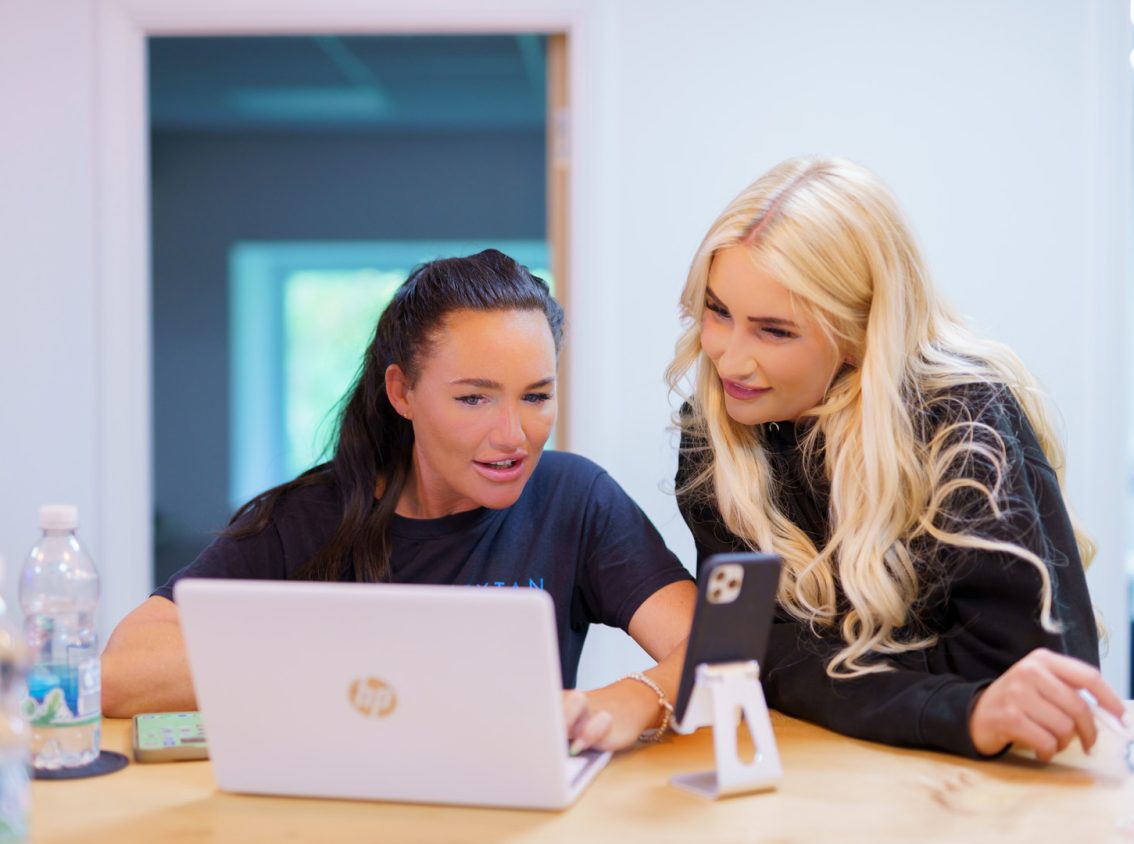 two women chatting at looking at a laptop