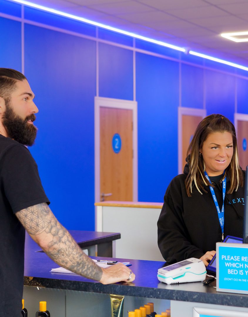 man standing at a customer service desk being served by a woman