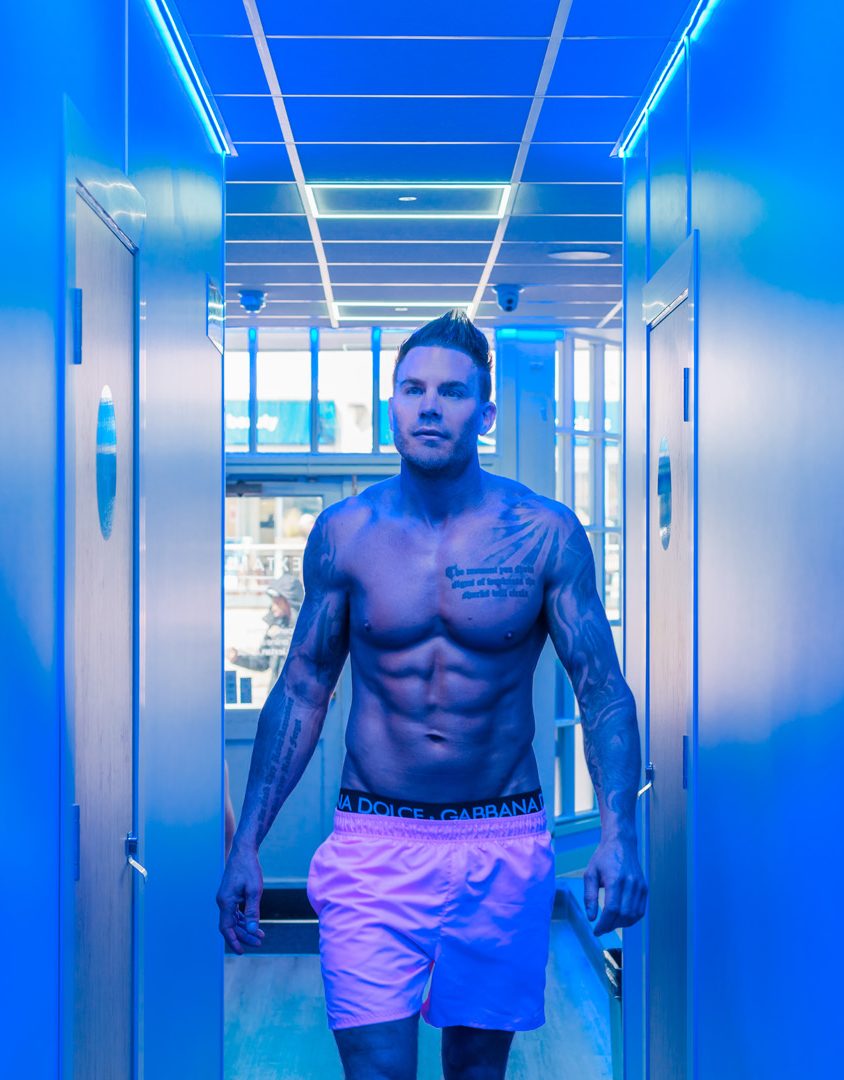 man in pink trunks walking down a corridor