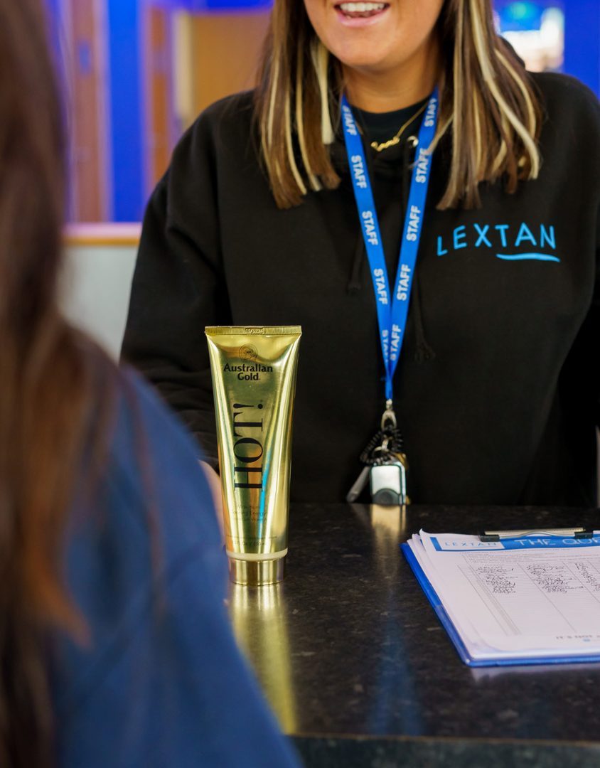 two women at a desk with tanning lotion